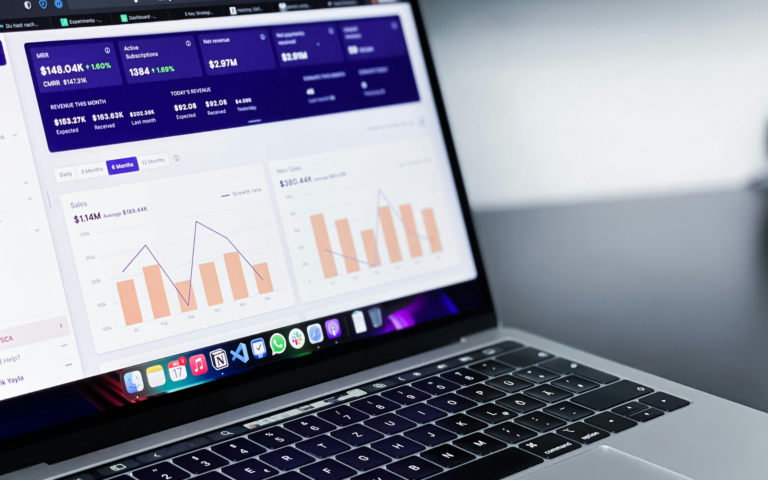 Laptop displaying a business analytics dashboard with revenue metrics, subscription counts, and monthly sales charts
